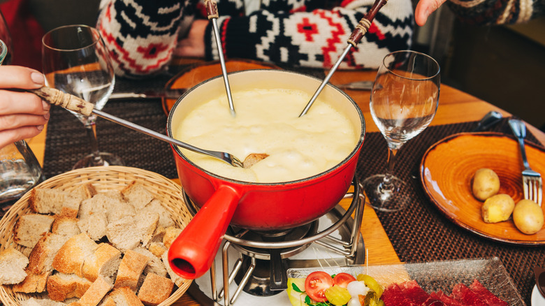 Cheese fondue with bread and dinner glasses 