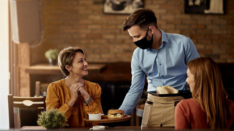 Waiter serving food to two women