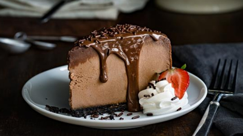 Chocolate Brigadeiro drizzled with syrup with whipped cream and strawberry on a plate