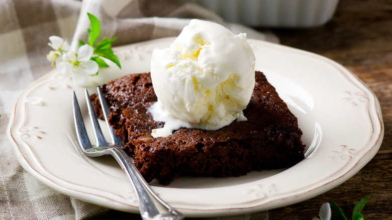 Chocolate brownie a la mode on a plate with a small flower accent