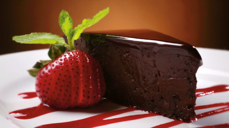 Chocolate Sin Cake sliced on a plate with a strawberry as an accent