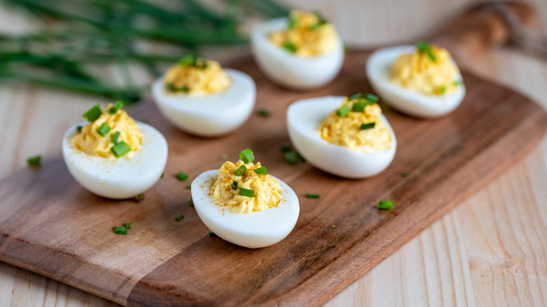 classic deviled eggs topped with chives on a cutting board