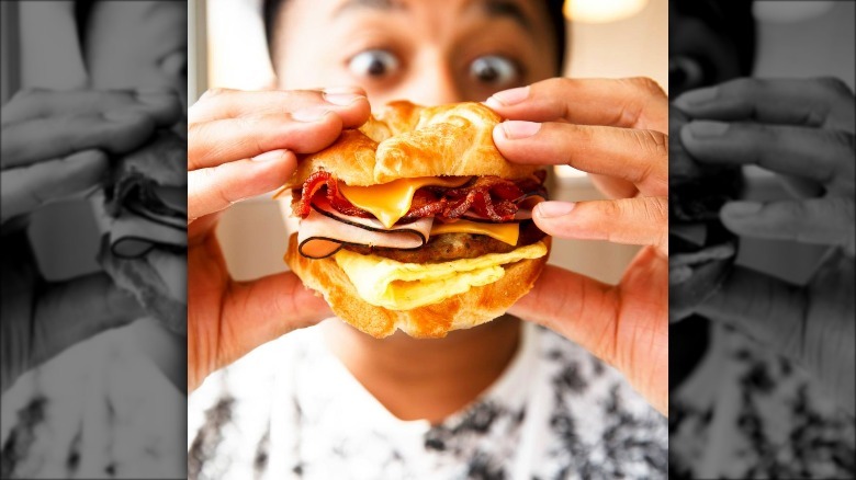 wide-eyed man eating breakfast sandwich