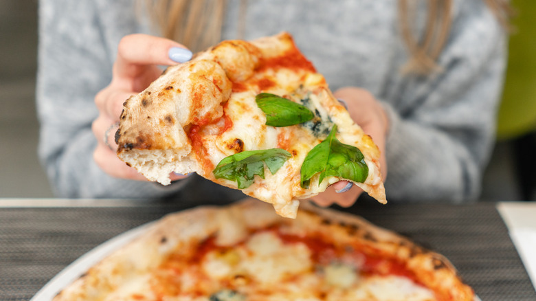 Woman holding a slice of pizza