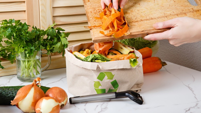 scraping vegetable peels into bag