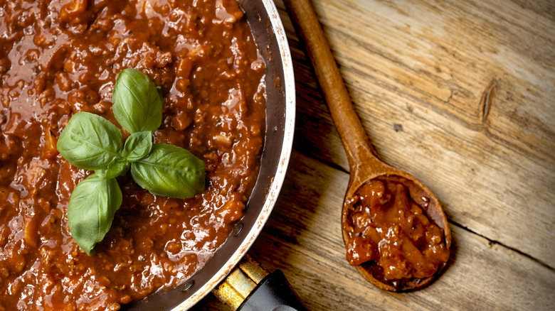 Ragu sauce in pan with wood spoon