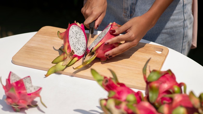 Woman slicing dragon fruit on a cutting board