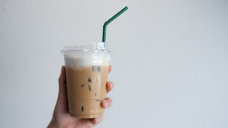 Person holding plastic cup with iced coffee