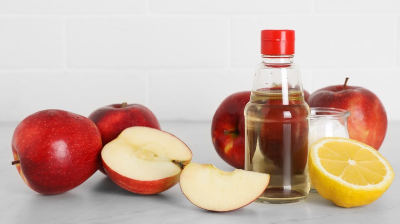 apples and lemon with vinegar in bottle