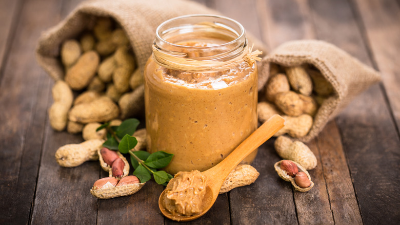 jar and spoon of peanut butter with bags of nuts