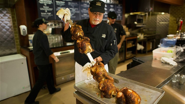 man with skewer of Whole Foods rotisserie chickens 