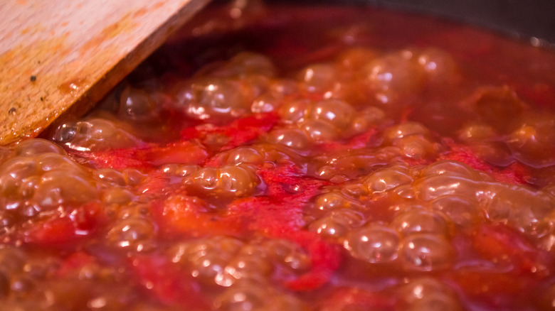 simmering tomato-based sauce with wooden spoon