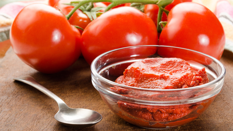 tomato paste in glass bowl and metal spoon