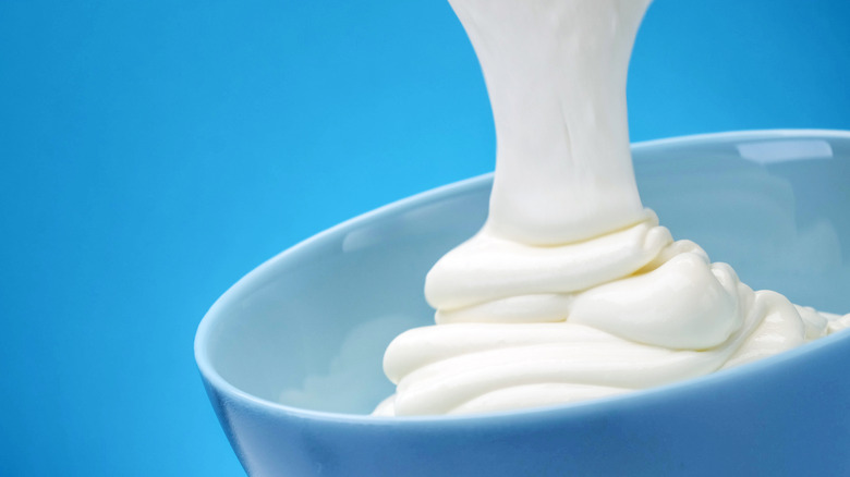 pouring Greek yogurt blue background