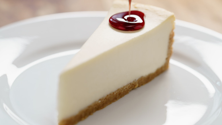 A slice of cheesecake with sauce drizzled over top