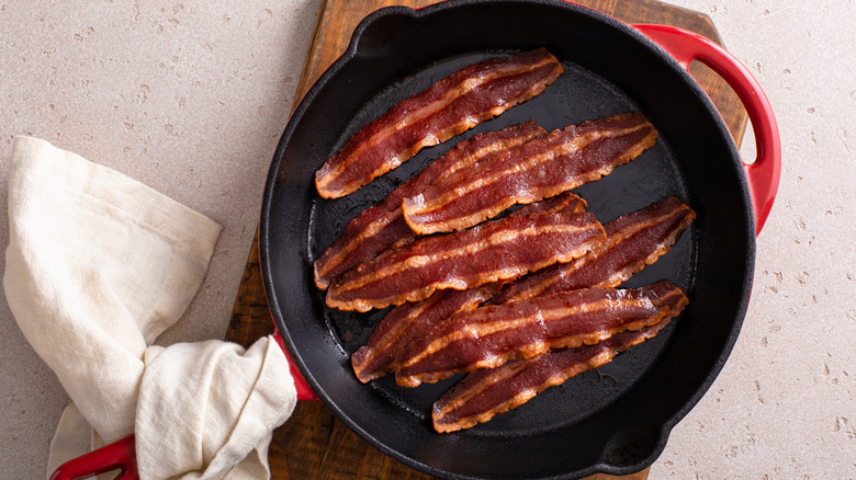 Thick strips of bacon in a frying pan