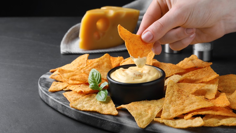 hand dipping chip in cheese