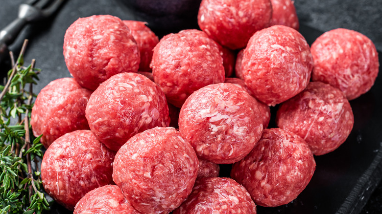 Raw meatballs on wooden board