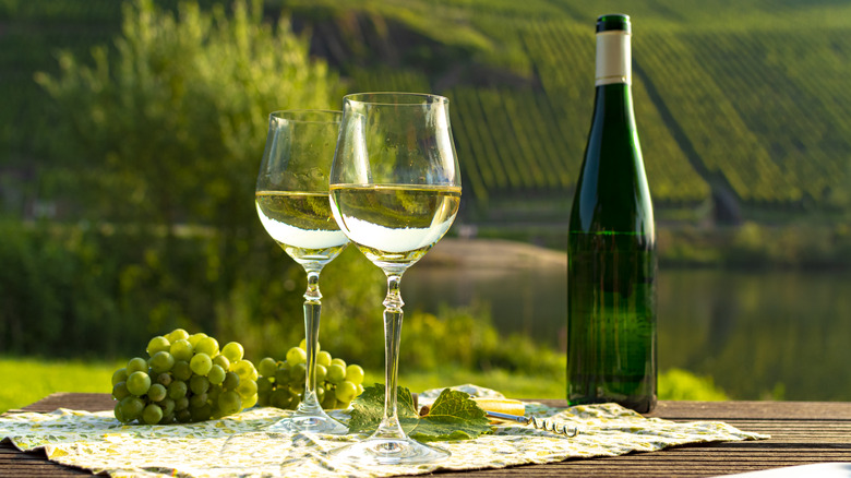 Two glasses of white wine beside a wine bottle