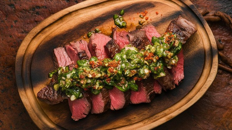 Sliced steak on board with chimichurri