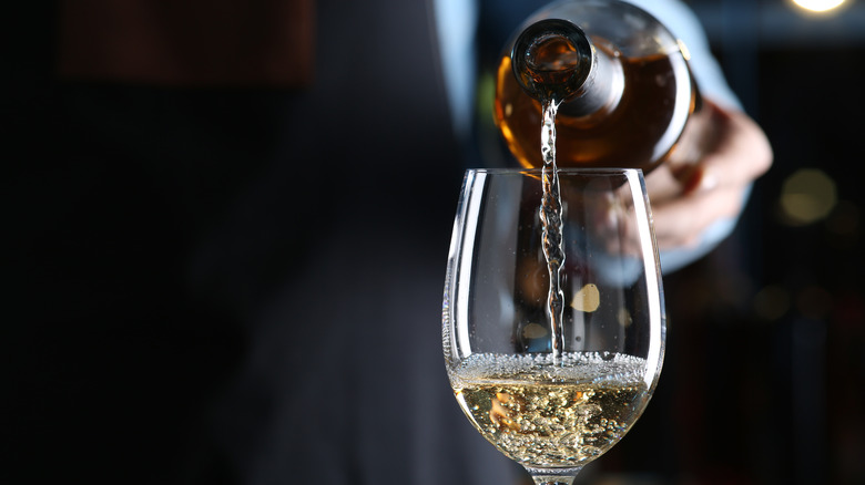 Server pouring white wine into glass