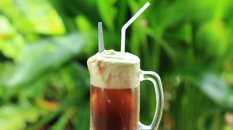 Root beer float against green background 