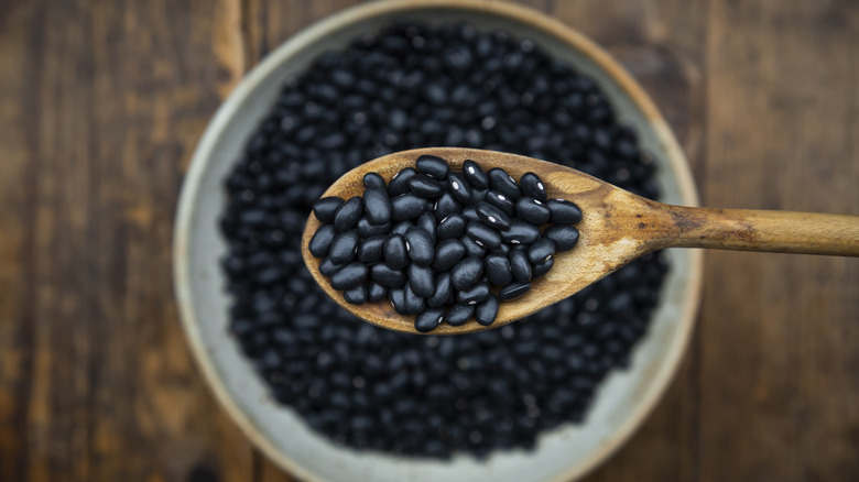 close up of black beans on wooden spoon