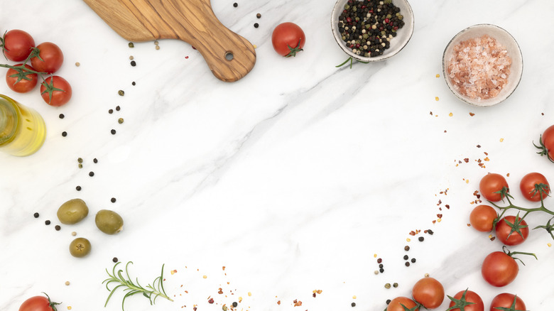 Tomatoes, oil, and spices on marble counter