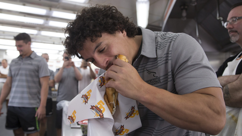 A man eating a Philly cheesesteak