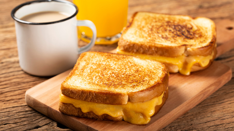 grilled cheese sandwiches on cutting board next to coffee