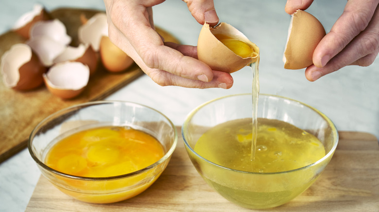 hands separating out egg yolk from egg white in two glass bowls