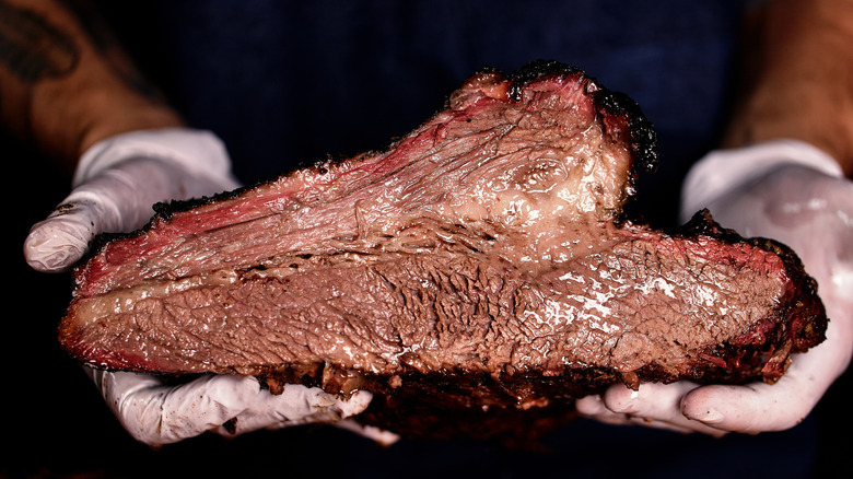 Juicy brisket held by gloved hands