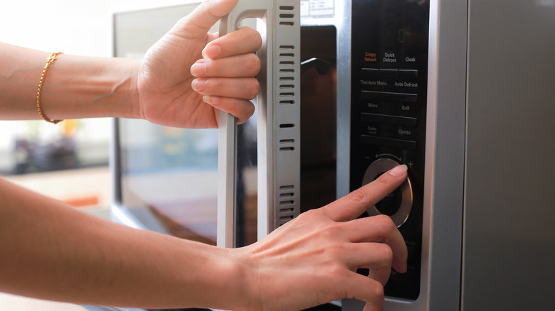 person setting timer on microwave