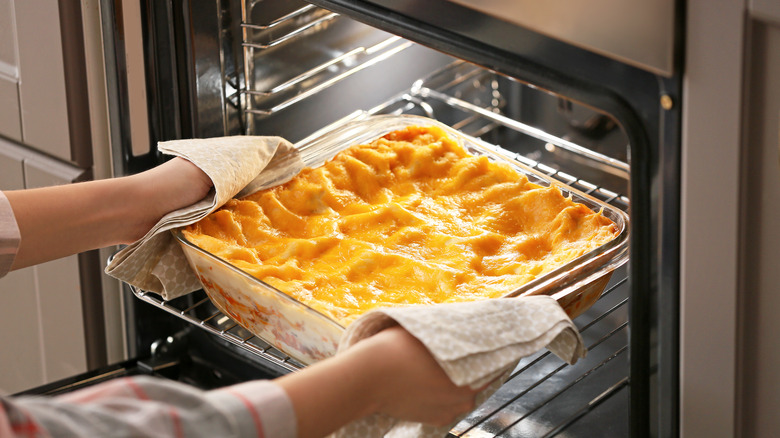 Lasagna dish being pulled out of oven after baking