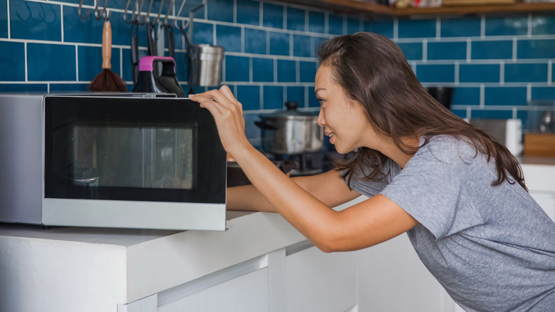 woman removing food from microwave