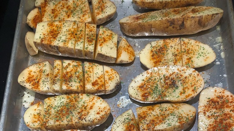 Uncooked scored and seasoned potatoes in a pan