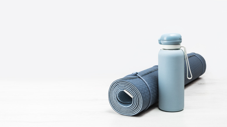 Blue metal water bottle next to a yoga mat