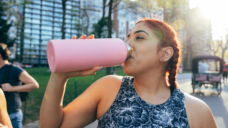 Woman drinking from a pink stainless steel water bottle