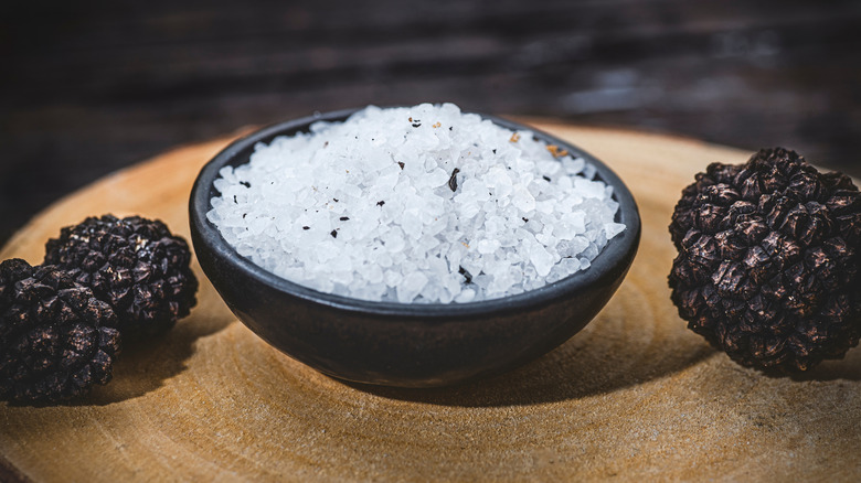 A bowl of truffle salt flanked by black truffles.