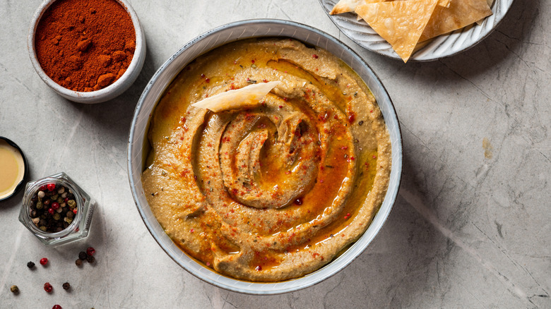 eggplant dip in bowl by paprika and whole pepper