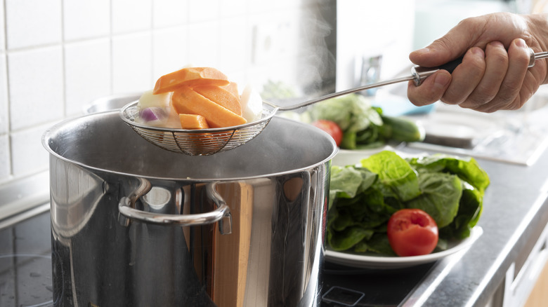 person blanching vegetables