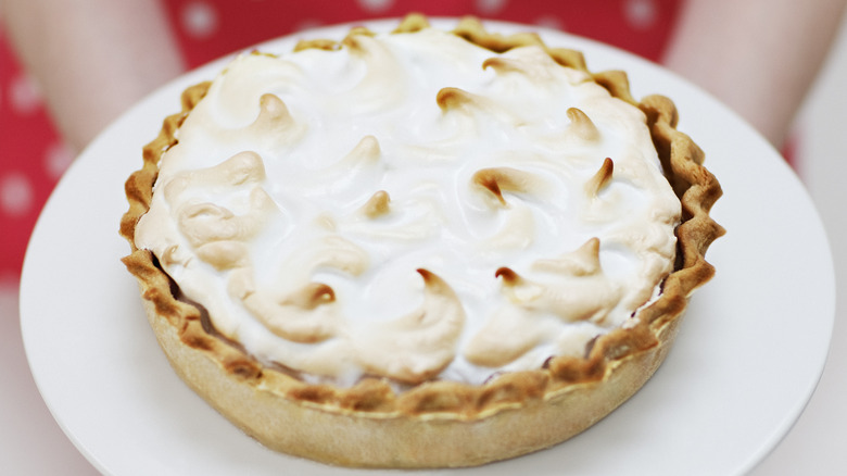 person holding whole meringue pie