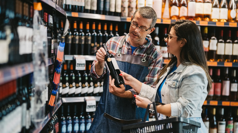 A customer talking to the shopkeeper in a wine store