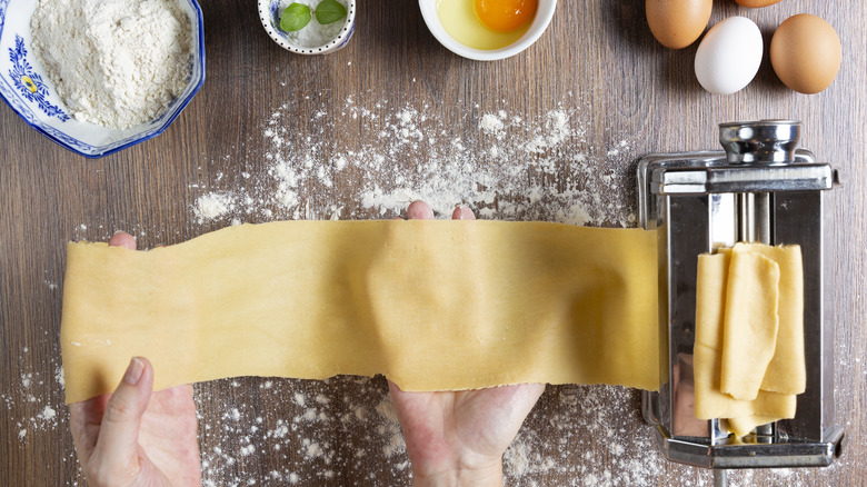 person running dough through pasta maker