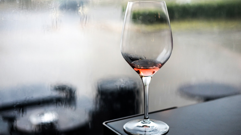 Nearly empty glass of rosé before rainy window