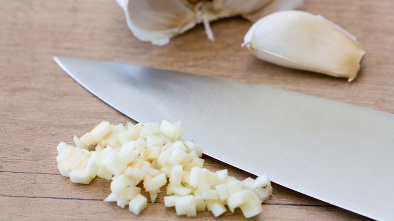 Chopped garlic on cutting board with knife 