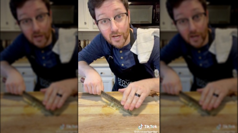 man in apron chopping garlic