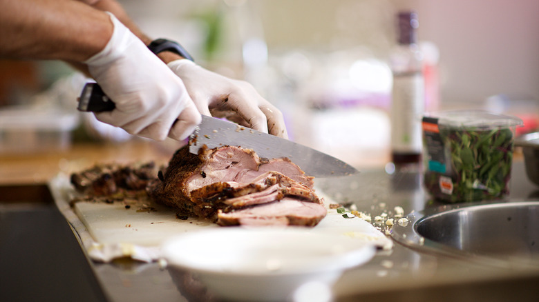 hands cutting roast meat with knife