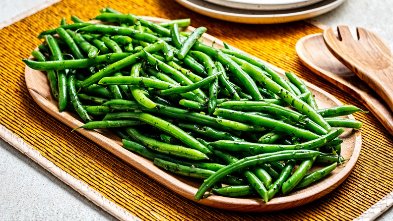 Seasoned green beans on a wooden platter.