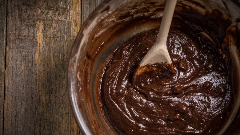 wood spoon mixing brownie batter in a bowl